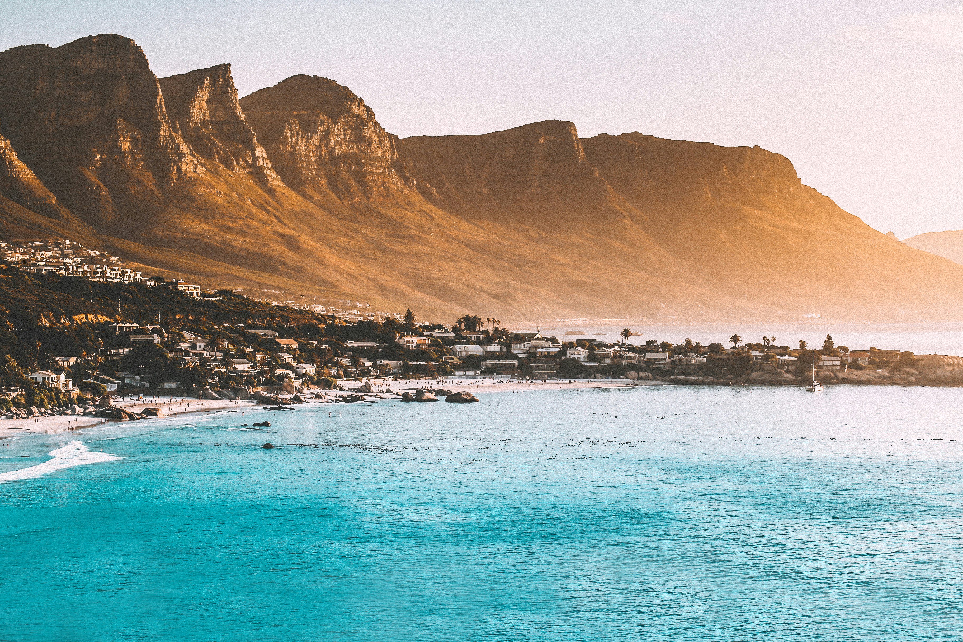 photography of buildings beside seashore and mountain during daytime